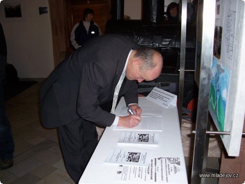Fotografie Závěrem pan starosta zapisuje do pamětní knihy vernisáže své dojmy.