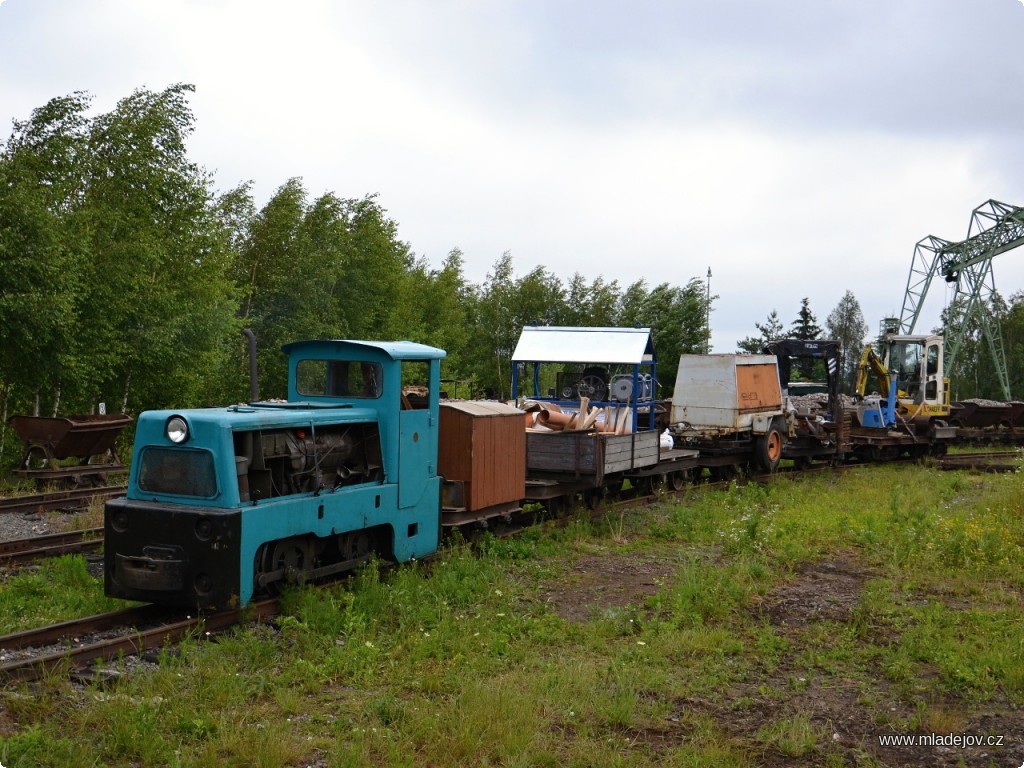 Fotografie Na trať vyráží téměř veškerá dostupná mechanizace – za lokomotivou BN-60 H zastřešený pneumatický kompresor, dále elektrocentrála, hydraulická ruka, vibrační deska a bagr.