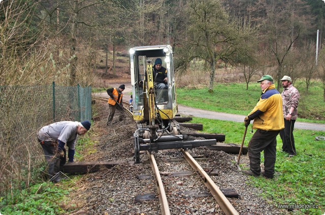 Fotografie Letos nám již druhým rokem pomáhá poklad z&nbsp;dílny BH RAIL - hydraulický vytahovák pražců umístěný na dvoucestném bagru, který dokáže měnit pražce bez nutnosti rozebírání kolejových polí. Díky němu jde práce hezky od ruky.