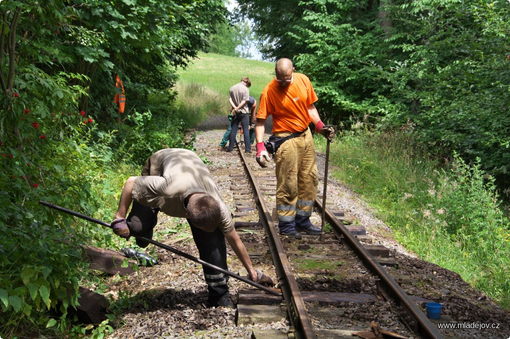 Fotografie A zadní družstvo poté připevní pražec zpět ke kolejnici.